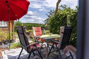 黑欣根Baumelt Ferienwohnung的庭院配有桌椅和红色遮阳伞。