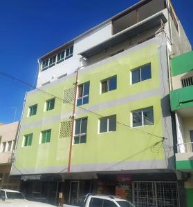 普拉亚Homing Plateau - Apartment in the city of Praia的一座黄色和白色的建筑,前面有汽车停放