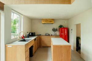 轻井泽Hutte Gartenland -KAIZUKA- ヒュッテ ガーテンラント カイヅカ的厨房配有红色冰箱和木制橱柜
