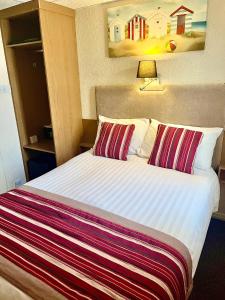布莱克浦伯翰姆伍德法院酒店的配有两张枕头的床的酒店客房