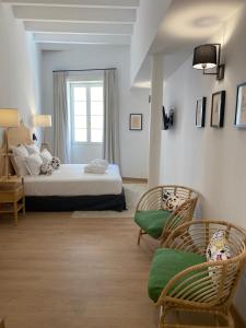 休达德亚Hotel Maïa的一间卧室配有一张床、两把椅子和一个窗户