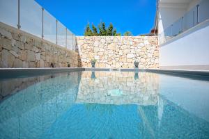 诺托玛丽娜Villa Carlotta con piscina的一座拥有石墙和蓝色海水的游泳池