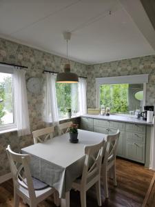 韦特兰达Mysig stuga i naturskönt område.的厨房配有白色的桌子、椅子和窗户。