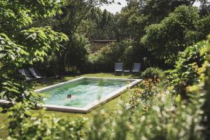 普罗旺斯艾克斯Les Lodges Sainte-Victoire Hotel & Spa的在院子里的游泳池游泳的人