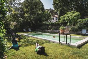 普罗旺斯艾克斯Les Lodges Sainte-Victoire Hotel & Spa的一群人躺在游泳池边的草地上