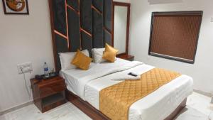 孟买Hotel Palms Residency, Chembur Mumbai的一间卧室配有一张带黄色枕头的大床