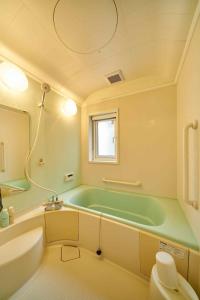 札幌Guest House Kingyo - Vacation STAY 14499的一间带绿色浴缸和窗户的浴室
