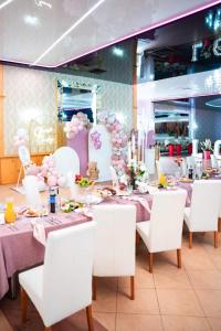 WielogóraHotel U Grubego的用餐室配有桌子、白色椅子和粉红色装饰