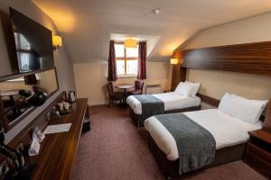 布莱克本The Fernhurst by Greene King Inns的酒店客房设有两张床和一张桌子。