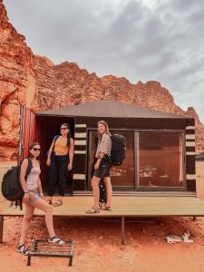 瓦迪拉姆Desert Bird Camp的三名妇女站在公共汽车前的木台上