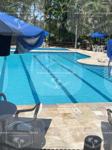 圣劳伦斯海滨Flat Perfeito Flat Amarilis em Riviera São Lourenço com café da manhã e enxoval completo praia e piscina com trocas的一个带椅子和遮阳伞的大型蓝色游泳池