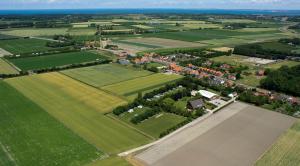 塞罗斯凯尔克Bed & Breakfast Carpe Diem Zeeland的享有田野的空中景致,拥有房屋和树木
