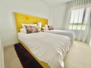 La MairenaLa Cala Golf - Luxury 3bed apartment - First line golf view的一间卧室设有两张带白色床单的床和窗户。