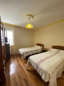 庞特维德拉PENSIÓN SANTA CLARA的一间卧室设有两张床、一个窗户和木地板。