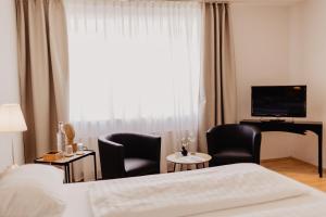 KollmarFährhaus Kollmar的酒店客房配有一张床、两把椅子和一台电视