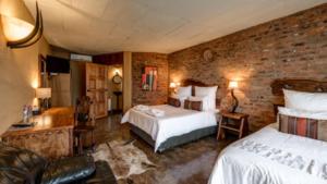 比勒陀利亚Ndlovu Lodge的一间卧室设有两张床和砖墙