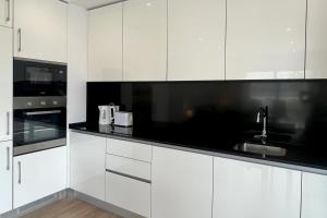 波尔蒂芒T2 Monte Residence by amcf的厨房配有白色橱柜和黑色台面