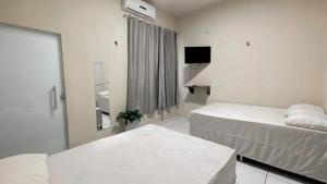 卡罗莱纳Pousada Villa Rica的白色的客房配有两张床和电视。