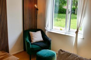 WarmleyHome in Longwell Green的窗前带枕头的绿色椅子