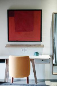 会安Kaia Gallery Hotel Hoi An的一张桌子、椅子和墙上的绘画
