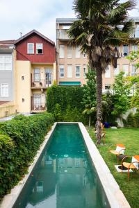 波尔图Hotel Tipografia do Conto by Casa do Conto的棕榈树和建筑的庭院内的游泳池