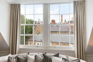 伦敦Wonderful Knightsbridge Apartment by Harrods的一张坐在大窗户前的白色沙发