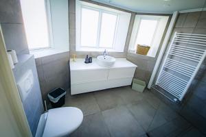 韦斯特曼纳埃亚尔Guesthouse Holl的一间带白色水槽的浴室和两个窗户