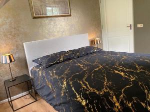 GeesterenB&B Erve Möskert的一间卧室配有一张带两盏灯的黑色和金色床。