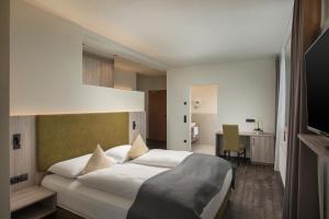 布鲁尼科Schönblick - Sport & Active Hotel的卧室配有一张白色大床和一张书桌