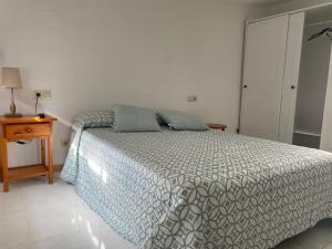 卡尔达斯·德·雷斯Apartamentos OLIVA的一间卧室配有一张床、一张桌子和一个床头柜