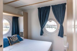 曼弗雷多尼亚Marina del Gargano Houseboat的一间卧室设有2扇带蓝色窗帘的窗户