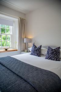 圣安德鲁斯Balmungo Cottage B&B的卧室配有带蓝色枕头的大型白色床