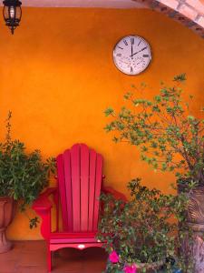 Mesa ColoradaHotel JADE的挂在墙上的红色椅子,挂着时钟