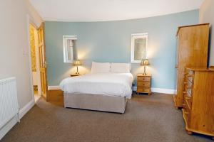 道宁斯Downings Coastguard Cottages - Type B-E的卧室配有白色的床和两盏灯。
