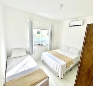 塞古罗港Paz e Sossego no Paraíso dos Pataxos com 2 Quartos Completo的白色客房的两张床,设有窗户