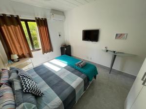 安格拉杜斯雷斯Angra dos Reis - Porto Bali - SUÍTE no Porto Bali Resort的一间卧室配有一张床、一张沙发和一台电视。