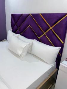 莱基Bamod Hotel and Suites的一张带白色枕头的床和紫色床头板