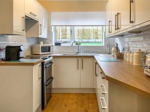 StaveleyHarris House的厨房配有白色橱柜和木制台面