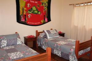 安加罗阿Camping Hostal Tipanie Moana Aeropuerto Centro的卧室配有两张床,墙上挂着一幅画