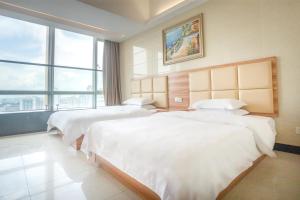 广州广州市骏田国际酒店公馆的酒店客房设有两张床和大窗户。