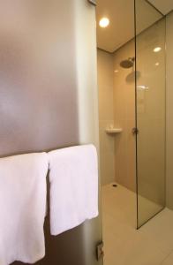 马尼拉Red Planet Makati Amorsolo的一间带玻璃淋浴和白色毛巾的浴室