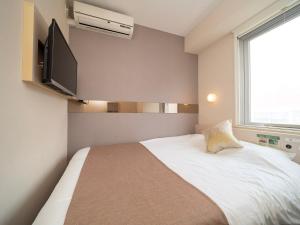 东京Super Hotel Premier Akasaka的卧室配有一张床铺,墙上配有电视
