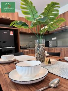 淡文Ojies Home Sunway Onsen Suites 2BR Theme Park View的一张桌子,上面放着两个碗,一个花瓶,上面放着植物