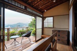 热海new! 熱海桃山邸　Atami terrace villa 〜Sauna & Onsen 〜的客房设有带桌椅的阳台。