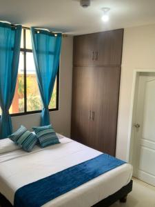 曼塔Reef Hostel Manta的一间卧室配有一张带蓝色窗帘的床和一扇窗户