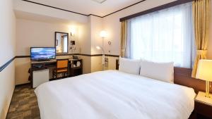 伊势崎市Toyoko Inn Gumma Isesaki Ekimae的酒店客房设有白色的床和电视。