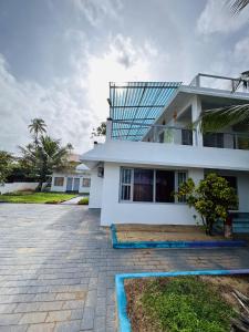 科钦Chameleon Beach Resort, Cherai的白色的房子,前面有一个庭院