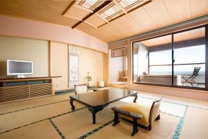 东伊豆町恩娜彤日东海大厦酒店的客厅设有桌子和大窗户