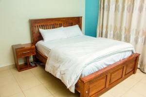 坎帕拉BRB Homes - Spacious 1 Bedroom Apatment - Bukoto, Kampala的一张带木制框架和白色床单的床