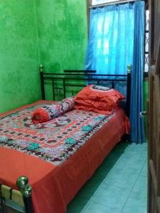 塞里布群岛Losmen Lima Saudara的一间卧室配有一张带红色床单和蓝色窗帘的床